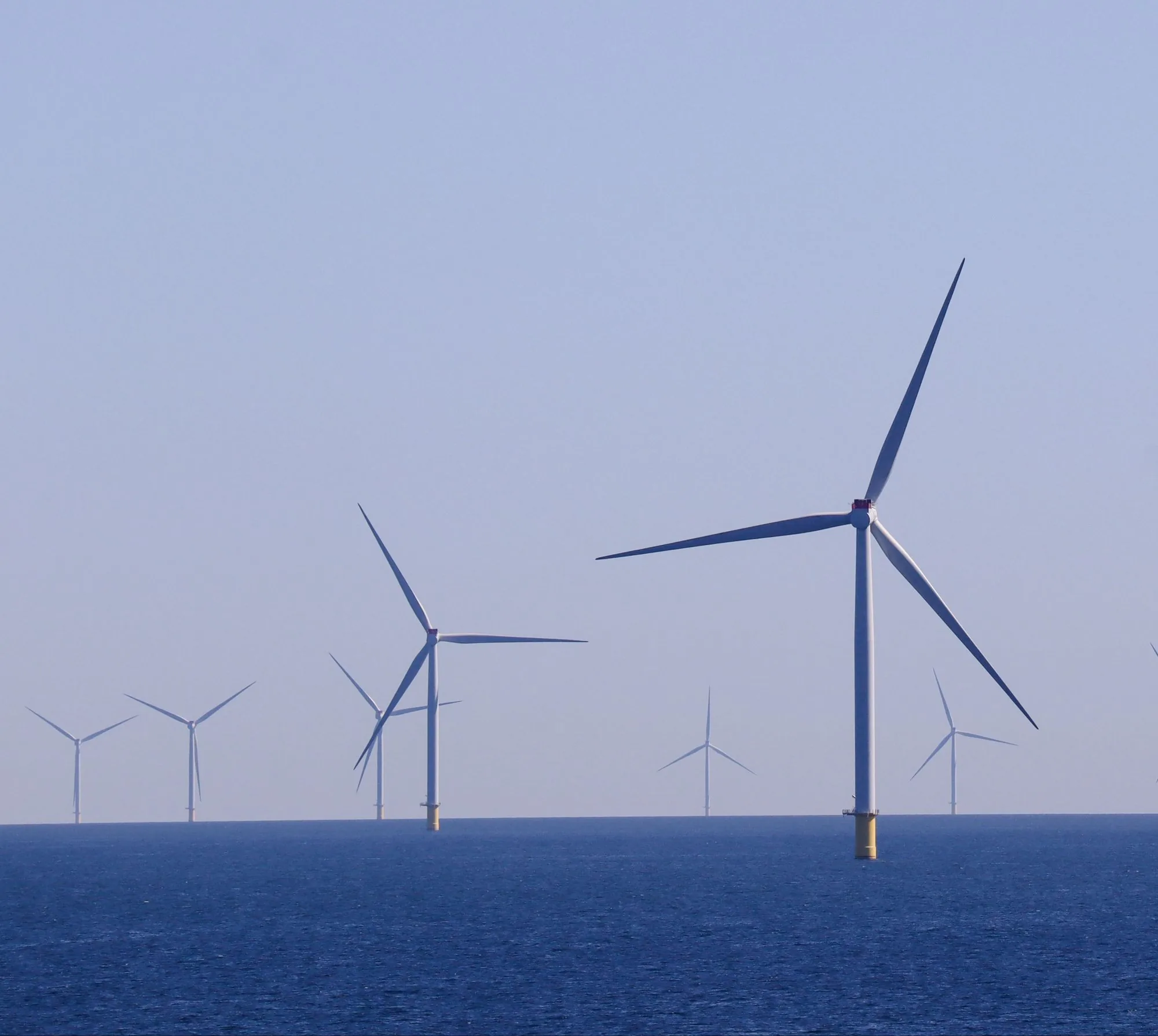 Offshore wind turbines standing in open blue sea